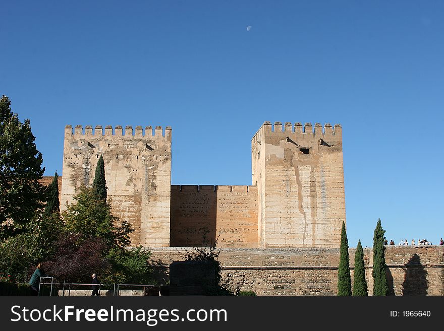 The Al Hambra, Grenada,Spain. Castle ramparts, garden and moon in the background. The Al Hambra, Grenada,Spain. Castle ramparts, garden and moon in the background