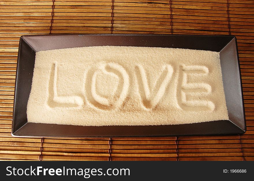 Love is written on sand against bamboo background. Love is written on sand against bamboo background