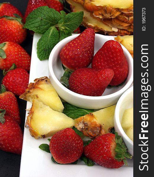 Fruit plate with strawberries and pineapple on black background. Fruit plate with strawberries and pineapple on black background