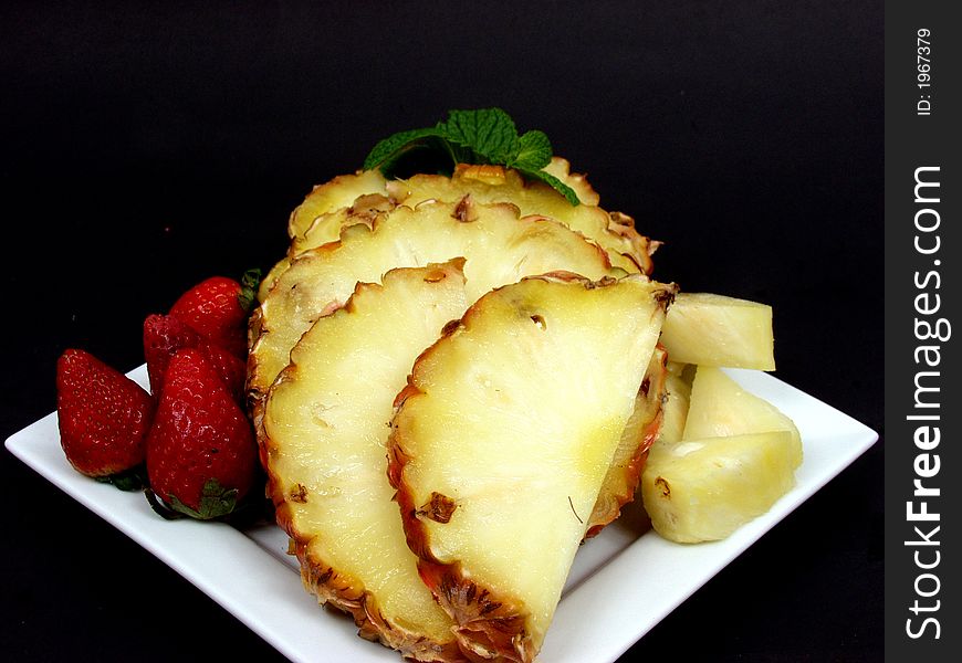 Fruit plate with strawberries and pineapple on black background. Fruit plate with strawberries and pineapple on black background