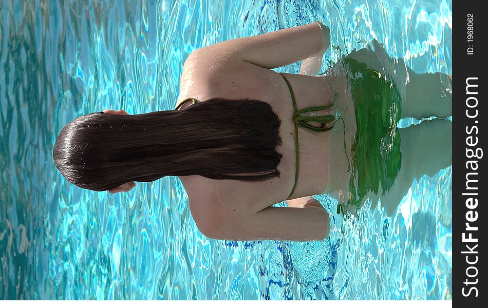 The back of a girl in the pool with long wet hair. The back of a girl in the pool with long wet hair