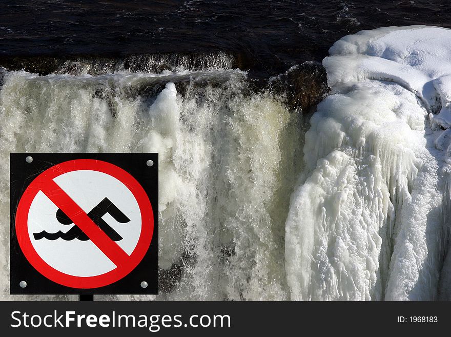 No swimming sign on icy waterfall