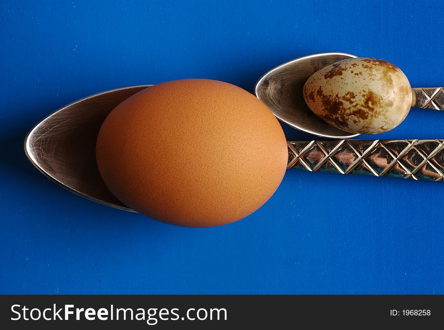 Two eggs and two spoons on blue background. Two eggs and two spoons on blue background