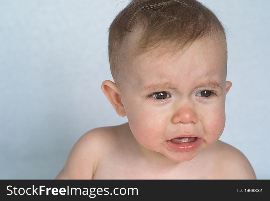 Image of cute whining baby sitting in front of a white background. Image of cute whining baby sitting in front of a white background