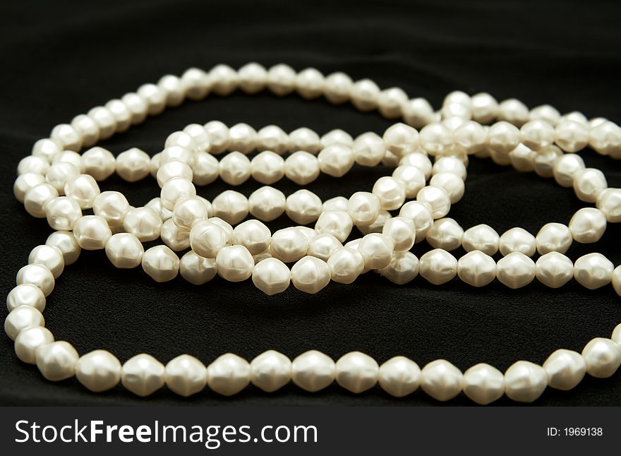 White real pearls on black velvet material background. White real pearls on black velvet material background.