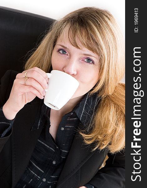 A blond woman in a black suit drinking a cup of coffee. A blond woman in a black suit drinking a cup of coffee