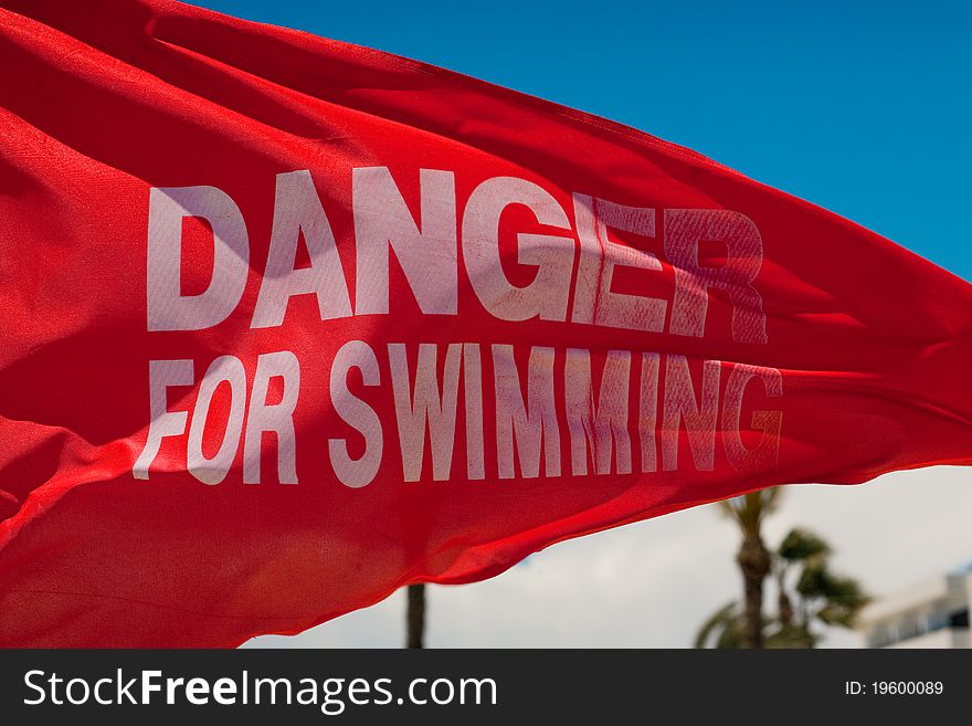 Waving in the wind red flag titled Danger for swimming. Waving in the wind red flag titled Danger for swimming