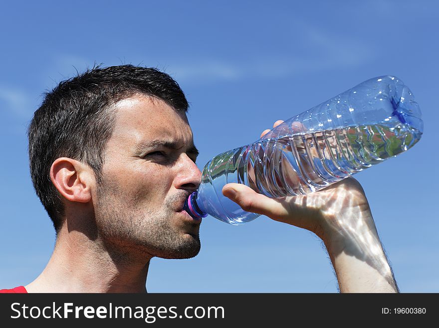 Young man drinking water in blue sky