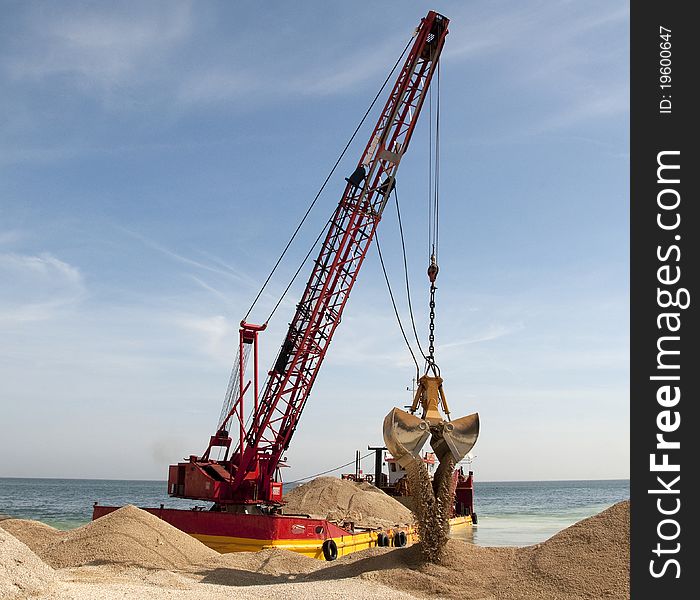 Bucket is downloading sand over the beach. Bucket is downloading sand over the beach