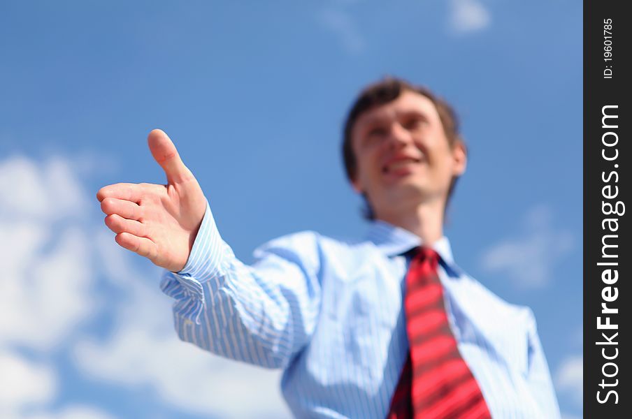 Young businessman in a blue shirt and red tie giving a hand for a handshake