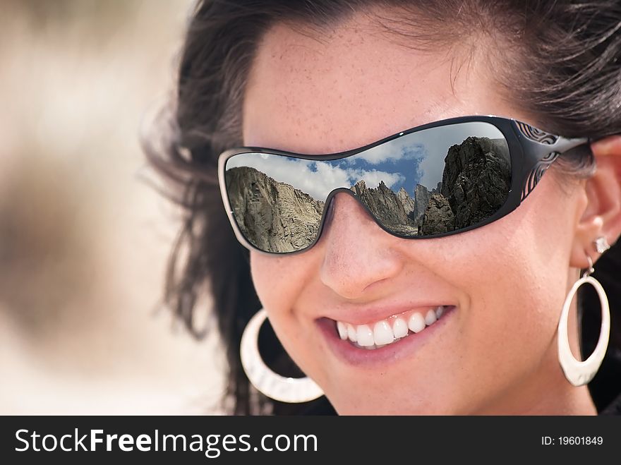 Woman with a reflection of a mountain range in her sunglasses. Woman with a reflection of a mountain range in her sunglasses