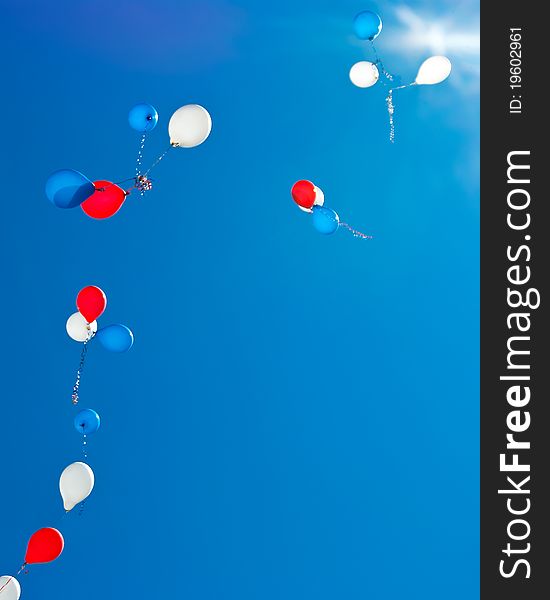 Colorful balloons, flying toward the sun against the blue sky