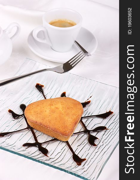 Small homemade heart-shaped cake served on a glass plate decorated with chocolate topping. Small homemade heart-shaped cake served on a glass plate decorated with chocolate topping.