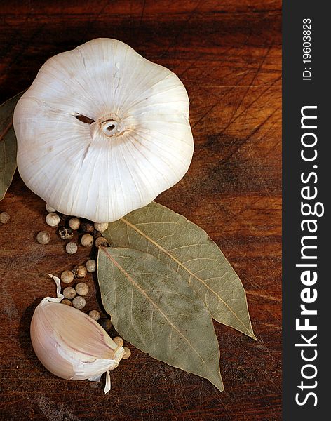 Garlic bulb and clove with spices on wooden cutting board (vertical image). Garlic bulb and clove with spices on wooden cutting board (vertical image)