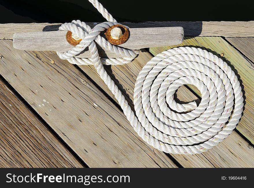 This is a photograph of a coiled rope tying a boat to a dock. This is a photograph of a coiled rope tying a boat to a dock.