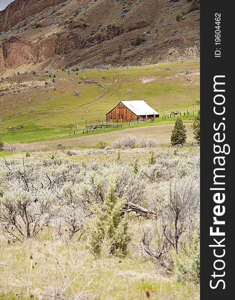 An old barn sits on the side of a hill overlooking the meadow below in central Oregon. An old barn sits on the side of a hill overlooking the meadow below in central Oregon.