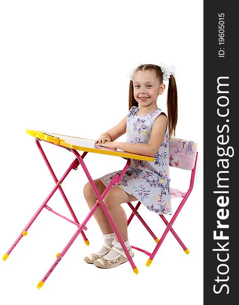 The little girl sits at a children's folding table
