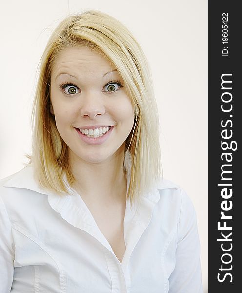 Wide eyed young blond woman in white shirt with surprised look. White background. Wide eyed young blond woman in white shirt with surprised look. White background
