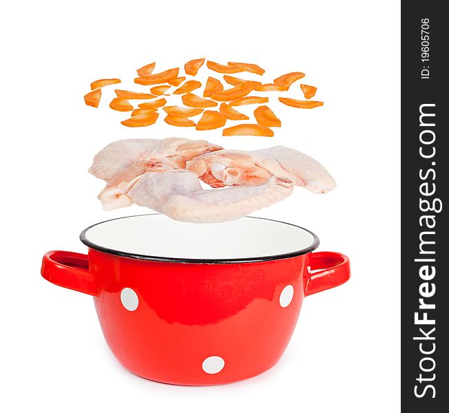 Red pot with white spots vintage with layers of chicken wings and carrots for soup preparation