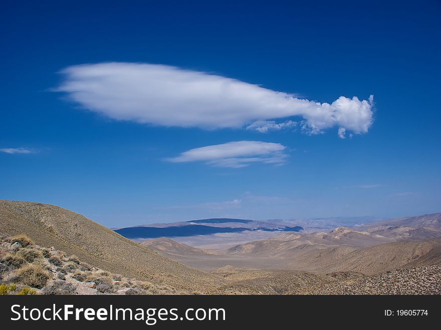 A zepplin-shaped cloud drifts lazily over the hills of Death Valley National Park. A zepplin-shaped cloud drifts lazily over the hills of Death Valley National Park.