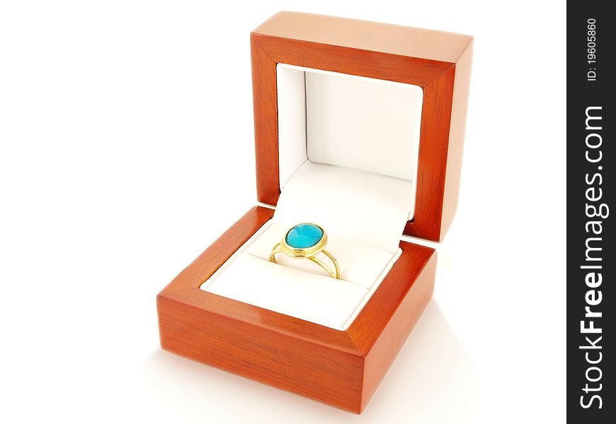 Blue gemstone on gold ring in a wooden box, isolated towards white. Blue gemstone on gold ring in a wooden box, isolated towards white