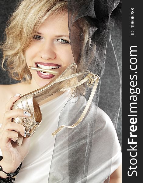 Beautiful lady holds shoe in the teeth