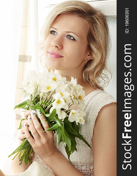 Girl sits on the window and holds the bouquet. Girl sits on the window and holds the bouquet