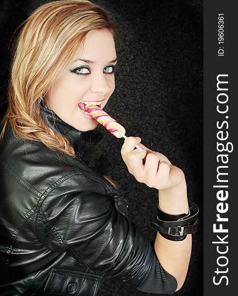 Girl eats candy against the dark background. Girl eats candy against the dark background