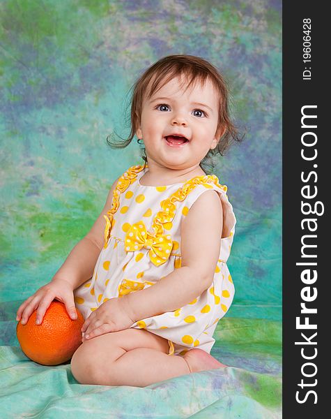 Little girl with the orange . she is sitting on the floor in studio