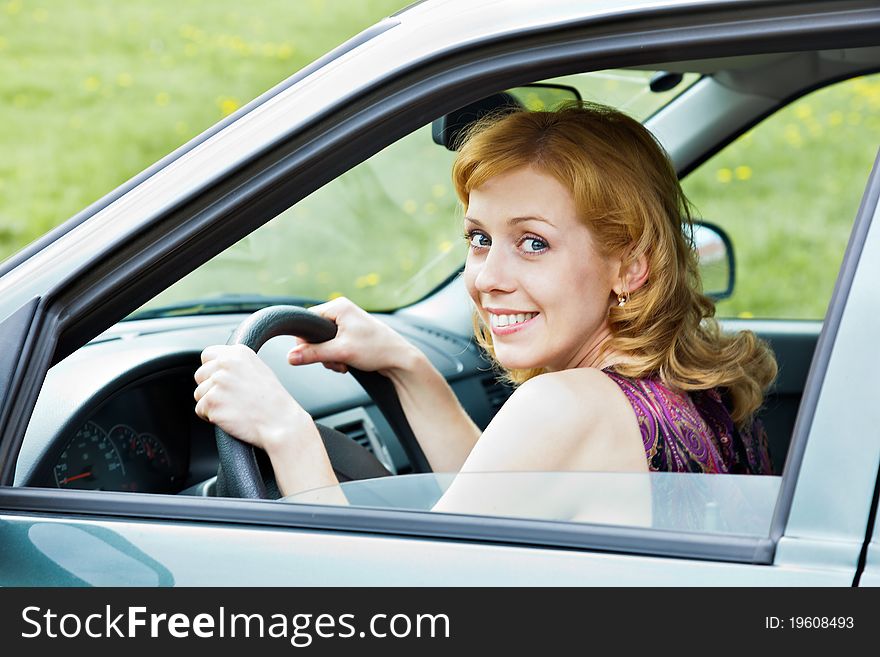 A cute smiling blond woman behind the wheel. A cute smiling blond woman behind the wheel