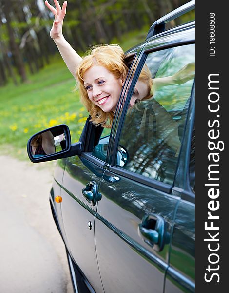 A smiling blond woman in a car is wagging
