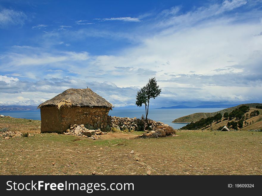 Lonely country house without windows and with a single tree in the yard, located on the shores of Lake Titicaca - the world's largest alpine lake. Incredibly deep blue sky and desert landscape, creating an ideal atmosphere for a relaxing meditation. Lonely country house without windows and with a single tree in the yard, located on the shores of Lake Titicaca - the world's largest alpine lake. Incredibly deep blue sky and desert landscape, creating an ideal atmosphere for a relaxing meditation.