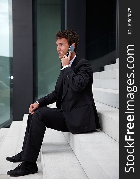 Business man siting on stairs with telephone