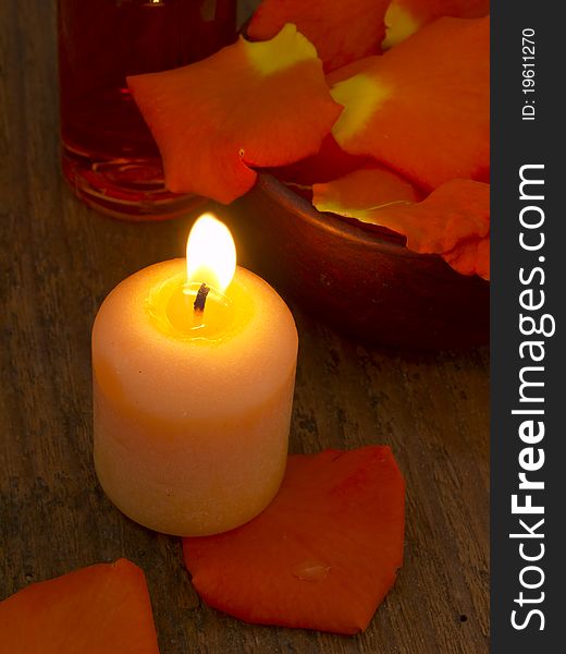 With burning candle and orange rose's petals. With burning candle and orange rose's petals
