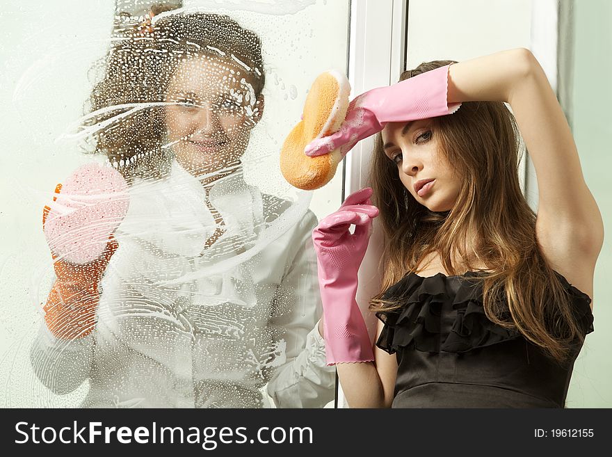 Attractive glamour girls washing the window with mop
