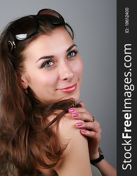 Close-up, portrait of a attractive brunette pensive girl with sunglasses on a head, isolated on grey. Close-up, portrait of a attractive brunette pensive girl with sunglasses on a head, isolated on grey