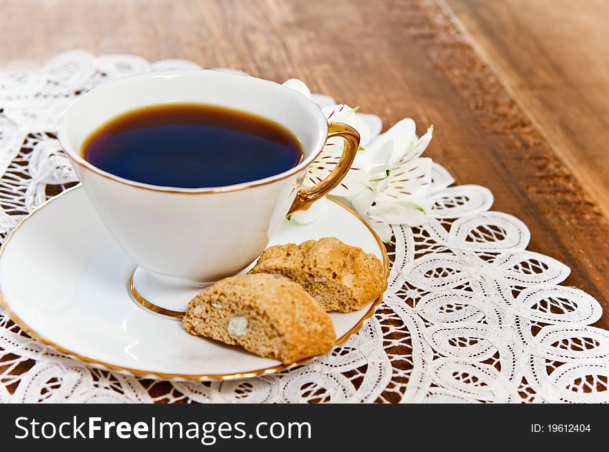 Cookies and coffee with flower on wooden background decorated with white lace napkin