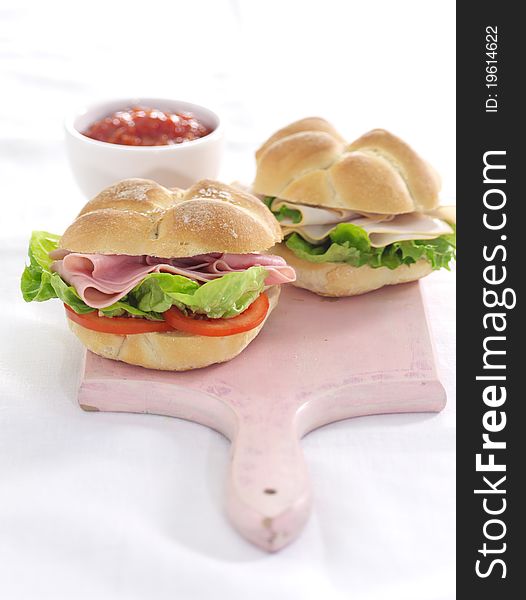 Ham salad rolls on a green tray with relish pot in background. Ham salad rolls on a green tray with relish pot in background