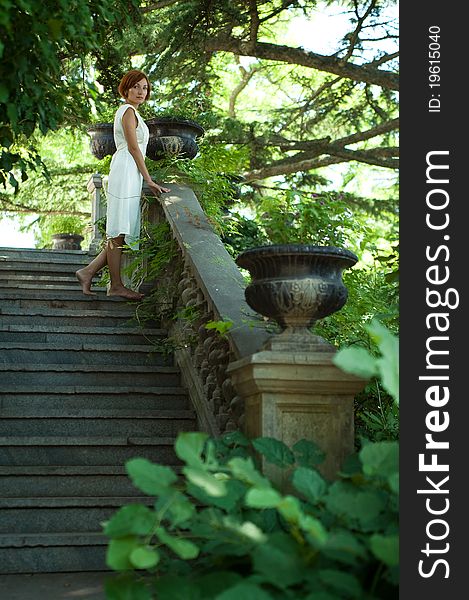 Beautiful young woman strolling through the old summer garden. Beautiful young woman strolling through the old summer garden