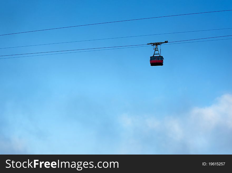 Ski lift is moving up high in the sky above the clouds