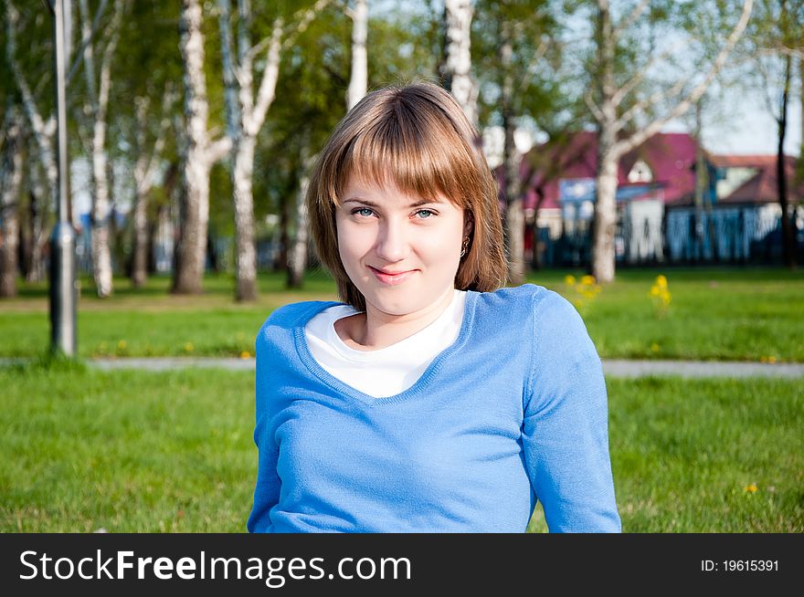 Smiling young girl sitting in the park. Smiling young girl sitting in the park