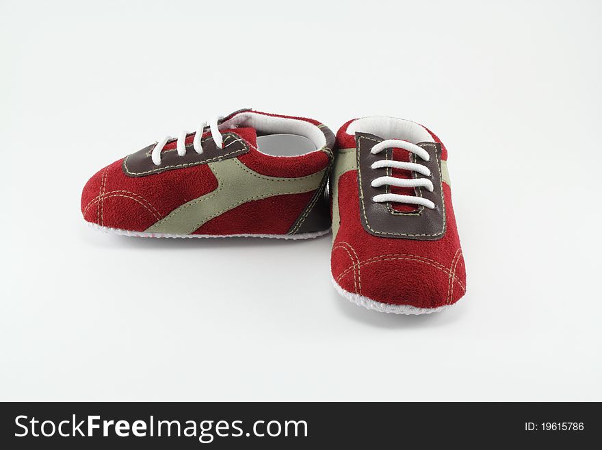 Baby sports shoes and red striped fabric. Baby sports shoes and red striped fabric