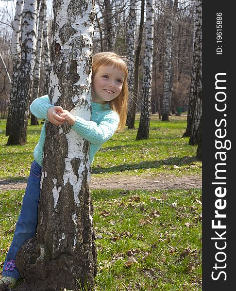 Smiling girl in birch grove in springtime