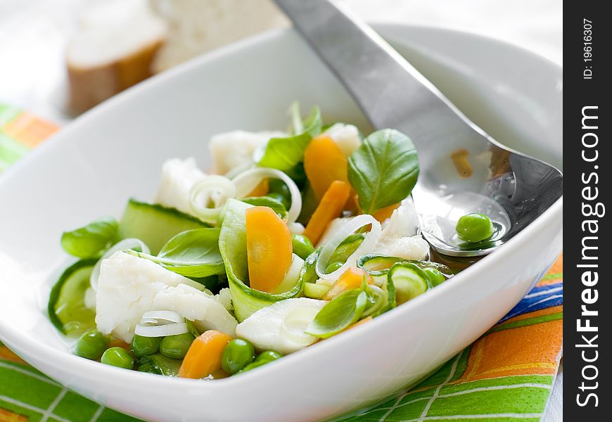 Vegetable soup with fish in a white plate