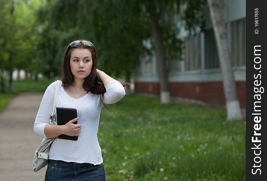 Girl in the campus alley with notebook looking right with space for text. Girl in the campus alley with notebook looking right with space for text