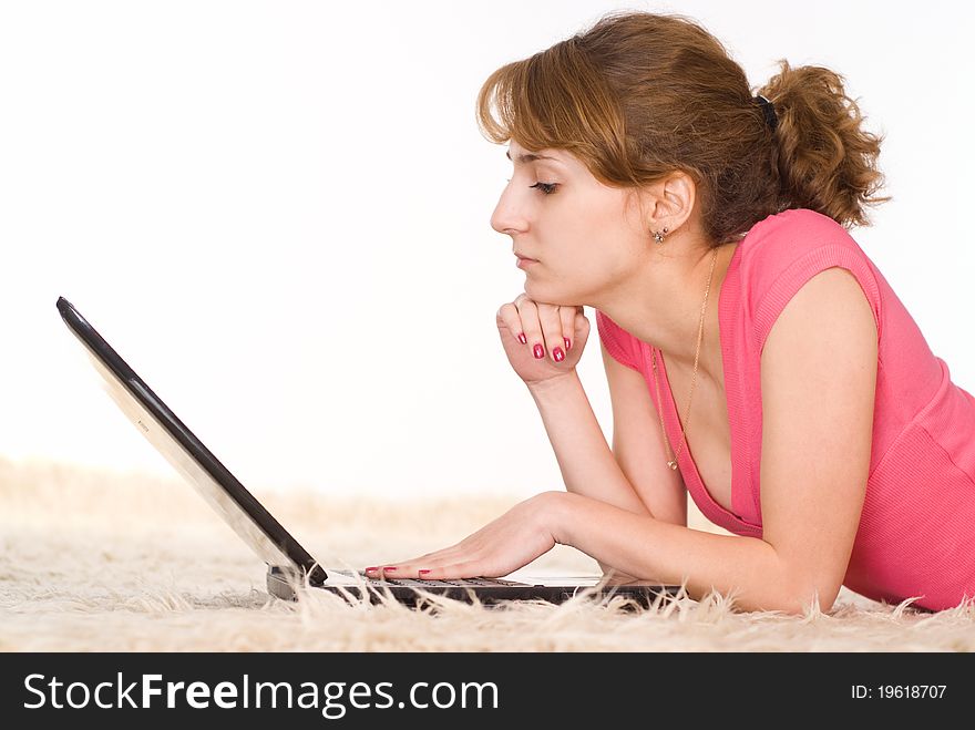 Beautiful girl lying on carpet with a laptop. Beautiful girl lying on carpet with a laptop