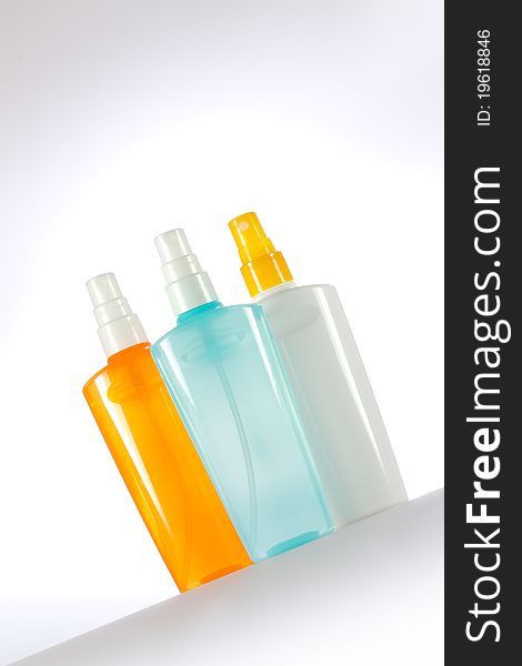 Colorful cosmetic sprays on a gray background. Vertical image