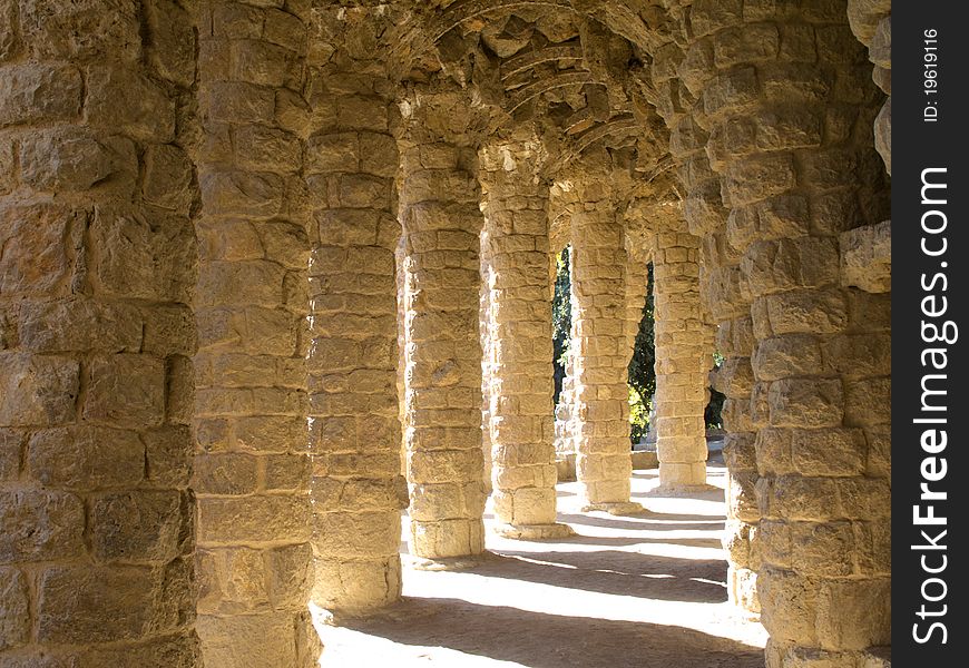 Colonnaded footpath under the roadway viaduct, with external columns sloping to take the diagonal thrust from the vault supporting the road in Park Guell, designed by Catalan architect Antoni Gaudi, is garden complex with architectural elements situated on the hill of el Carmel in the Gracia district of Barcelona, Catalonia, Spain. Colonnaded footpath under the roadway viaduct, with external columns sloping to take the diagonal thrust from the vault supporting the road in Park Guell, designed by Catalan architect Antoni Gaudi, is garden complex with architectural elements situated on the hill of el Carmel in the Gracia district of Barcelona, Catalonia, Spain.