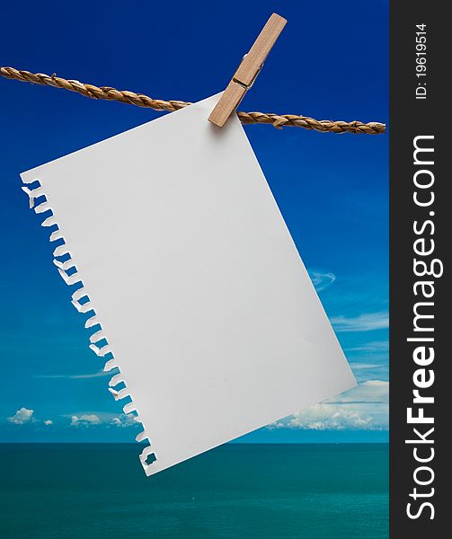 Close up of note pad and clothespins attached to a rope on blue sky background. Close up of note pad and clothespins attached to a rope on blue sky background