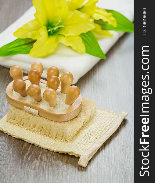 Studio shot view on the batching accessories wooden massager on the natural bast yellow flover with leaves on white cootton towels and all its on wooden boards. Studio shot view on the batching accessories wooden massager on the natural bast yellow flover with leaves on white cootton towels and all its on wooden boards